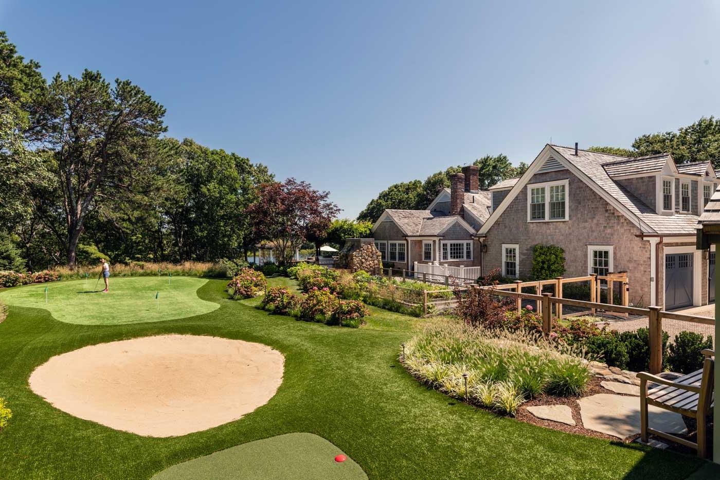 golf course with sand trap and person practicing next to a home