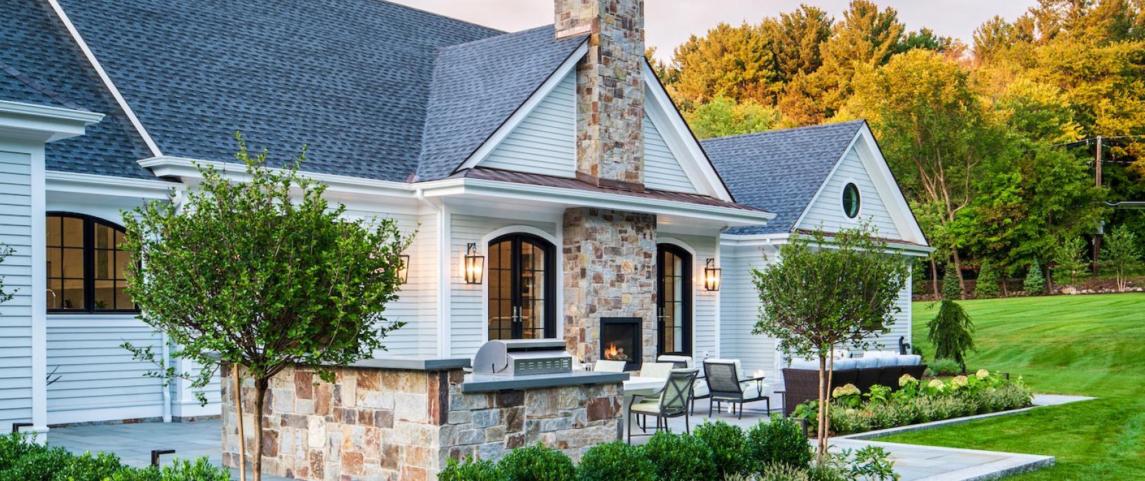 Outdoor patio with luscious landscape and stone grill and fireplace