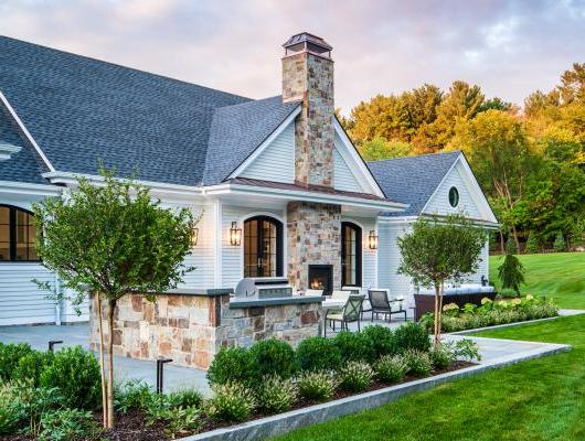 Outdoor patio with luscious landscape and stone grill and fireplace